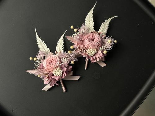 Two dusty pink preserved flower brooches with pale fern leaves and ribbon, shown together; sold individually.